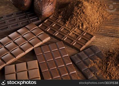 Chocolate bar, candy sweet, cacao beans and powder on wooden bac. Chocolate sweet, cocoa pod and food dessert background