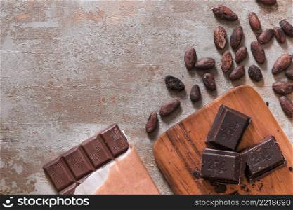 chocolate bar pieces with cocoa beans rustic backdrop