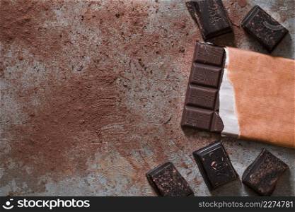 chocolate bar pieces with cocoa powder rustic backdrop