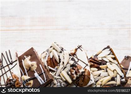 Chocolate bark on wood background. Assorted chocolate caramel bark pieces arranged on wooden background from above with copy space