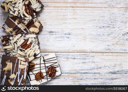 Chocolate bark on wood background. Assorted chocolate caramel bark pieces arranged on wooden background from above with copy space