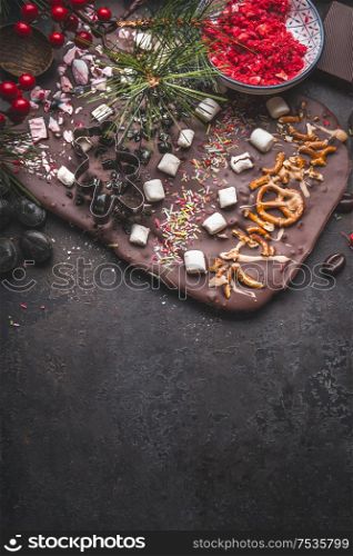 Chocolate bark with topping of caramel, marshmallows, nuts and candy . Christmas sweet gifts preparation on dark background with copy space. Top view