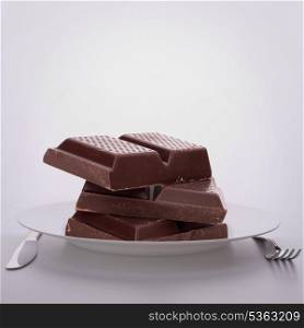 Chocolate bars stack on plate. Unhealthy eating concept.