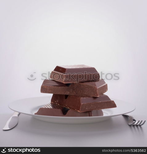 Chocolate bars stack on plate. Unhealthy eating concept.