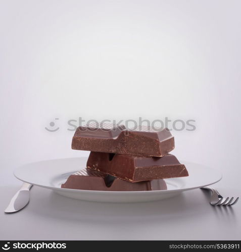 Chocolate bars stack on plate. Unhealthy eating concept.