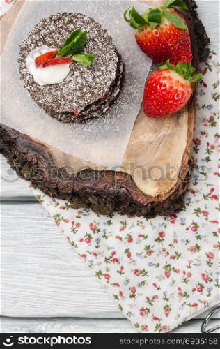 Chocolate belgian waffles with strawberries, whipped cream and mint leaf on wooden table. Top of view with copy space