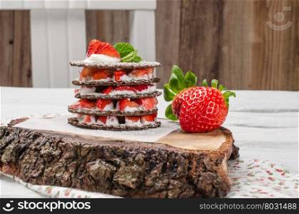 Chocolate belgian waffles with strawberries, whipped cream and mint leaf on wooden table