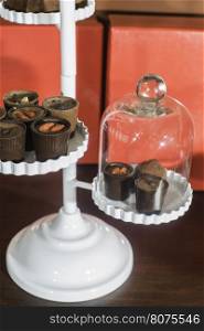 Chocolate bonbons in dish and cocoa on background