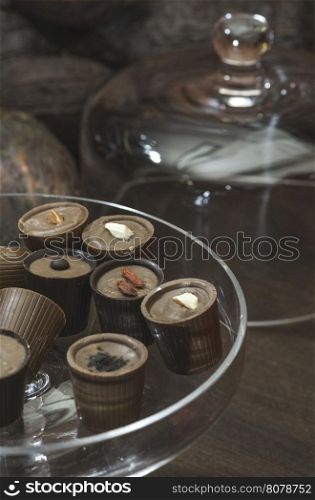 Chocolate bonbons in dish and cocoa on background