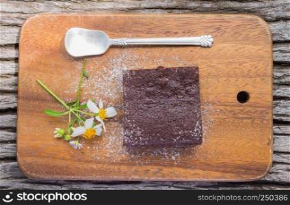 Chocolate Brownie Cake and Daisy Flower and Spoon on Chopping Board or Cutting board on Wood Table in Flatray or top table angle