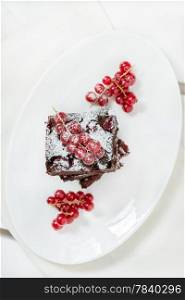 Chocolate brownie on white plate, overhead, selective focus