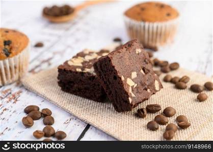Chocolate brownies on sackcloth and coffee beans on a wooden table. Selective focus.