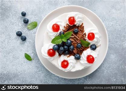 Chocolate cake, white cheesecake decorated with blueberries, cherry, brown chocolate and whipped cream