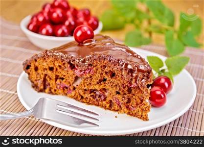 Chocolate cake with cherries on a plate, cherries, mint on a bamboo napkin on the background of wooden boards
