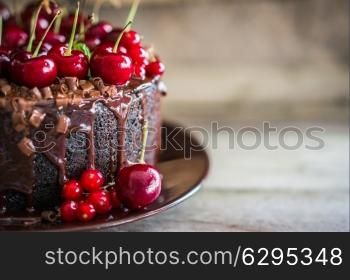 Chocolate cake with cherries on wooden background