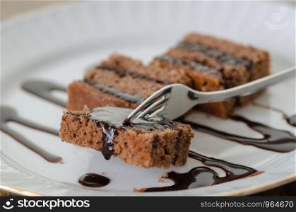Chocolate cake with chocolate on white dish.