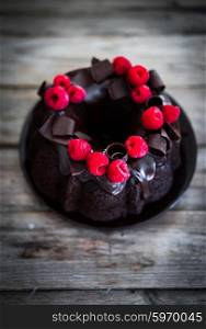 Chocolate cake with raspberries on rustic wooden background
