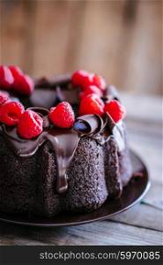 Chocolate cake with raspberries on rustic wooden background