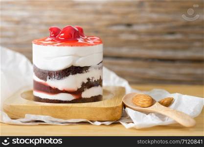 Chocolate cake with strawberry cherry and white cream on wooden table, A wooden spoon and almond paste close, close-up