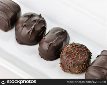 chocolate candies assortment in a white plate, close up