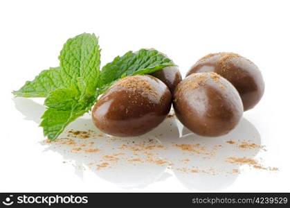 Chocolate candies on white reflective background.