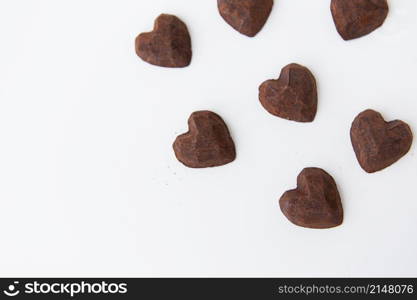 Chocolate candies with a truffle in the form of a heart on a white background, close-up. Place for an inscription. Chocolate candies with a truffle in the form of a heart on a white background, close-up. Place for an inscription.