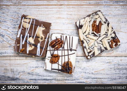 Chocolate caramel bark pieces. Three assorted chocolate caramel bark pieces as sweet dessert arranged on wooden background from above