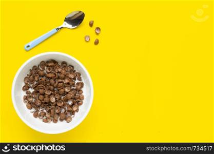 Chocolate cereal with milk on yellow background. Copy space