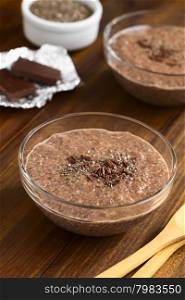 Chocolate chia seed pudding in glass bowl with chia seeds and chocolate shavings on top, photographed with natural light (Selective Focus, Focus in the middle of the chia pudding)