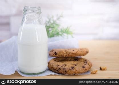 Chocolate chip cookies and a bottle of milk on a wooden table, Vintage look.