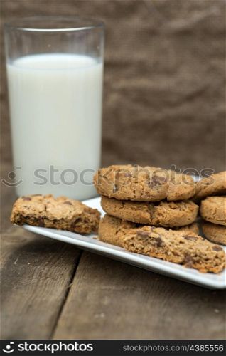 Chocolate chip cookies in rustic kitchen setting with glass of milk
