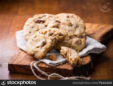 Chocolate chip cookies on napkin over olive wood board, selective focus