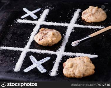 Chocolate chip cookies on noughts and crosses sugar grid, dark background, creative image, selective focus