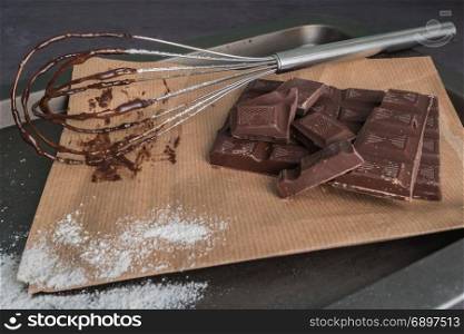 Chocolate chunks. Chocolate bar pieces and whisk on board.