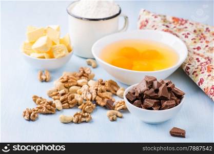 Chocolate chunks, eggs, butter, nuts and cup of flour. Ingredients for baking. Selective focus