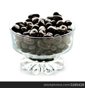 Chocolate coated cranberries or raisins in glass bowl on white background