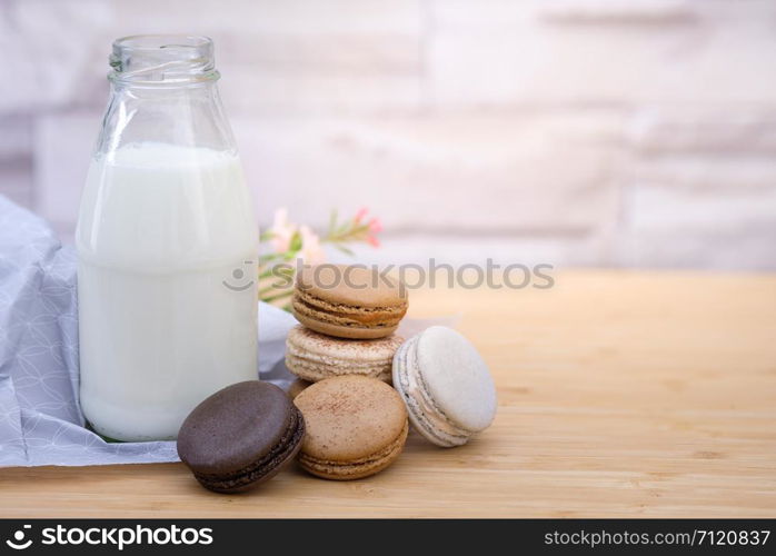 Chocolate, coffee macaroons and a bottle of milk on a wooden table in warm light, Vintage tone, Space to write.