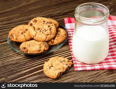 Chocolate cookie and glass of milk on red napkin on brown wooden table. Dairy product concept. Chocolate cookie and glass of milk