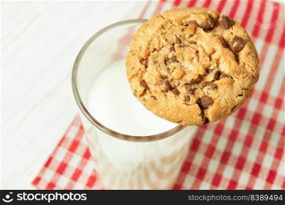 Chocolate cookie and glass of milk on red napkin on white wooden table. Dairy product concept. Chocolate cookie and glass of milk