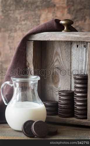 Chocolate cookies with creamy filling with jug of milk
