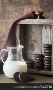 Chocolate cookies with creamy filling with jug of milk