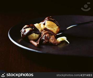 Chocolate covered profiteroles with spoon on plate with chocolate mouse