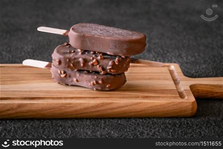 Chocolate-covered vanilla ice cream bars on the wooden board
