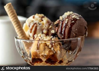 Chocolate, cream and caramel Roma ice cream in a glass bowl with hazelnut and chocolate sauce poured over it.