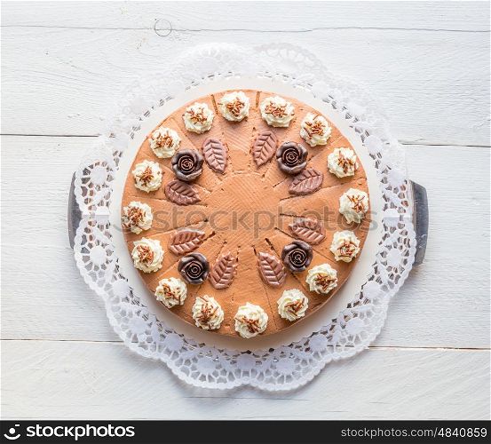 Chocolate cream cake on white wood with cake lace. Chocolate cream cake on white wood with cake lace.