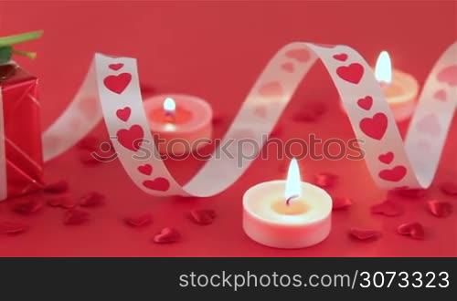 Chocolate cupcake against a red background with roses and gift at candlelight for a bright, fun and cheerful Valentines Day. Love and romance concept.