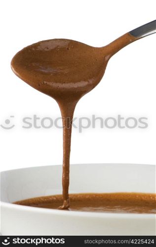 Chocolate dripping from spoon on white background.