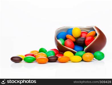 Chocolate egg with colorful small round candies on white background