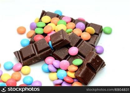 Chocolate filled candies in various bright colors and pieces of a chocolate bar