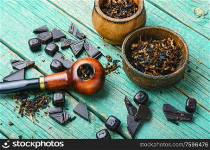 Chocolate flavored tobacco for smoking pipes.Tobacco pipe filled with tobacco.Smoking pipe on wooden table. Chocolate flavored tobacco pipe.
